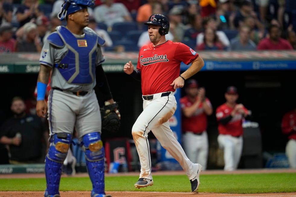 Cleveland Guardians' David Fry, right, scores behind Kansas City Royals catcher Salvador...