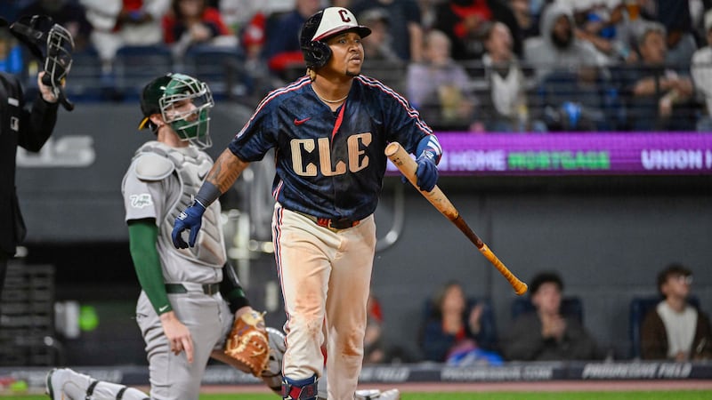 Cleveland Guardians' Jose Ramirez, right, watches his solo home run off Athletics relief...