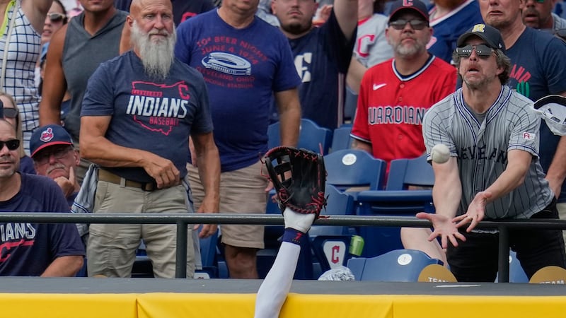 A fan reaches for the home run ball hit by Kansas City Royals' Josh Rojas that Cleveland...