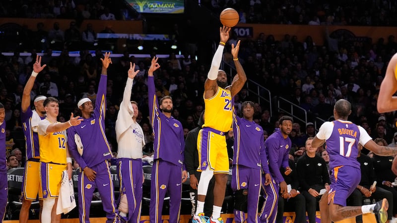 Los Angeles Lakers forward LeBron James, center, shoots as his teammates gesture from the...