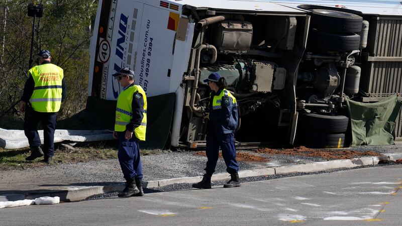 Police inspect a bus on its side near the town of Greta following a crash in the Hunter...