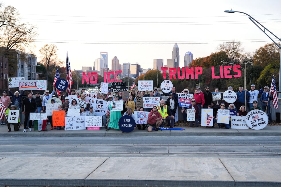 Protesters pose for a photo as they hold signs amid the arrival of federal law enforcement,...