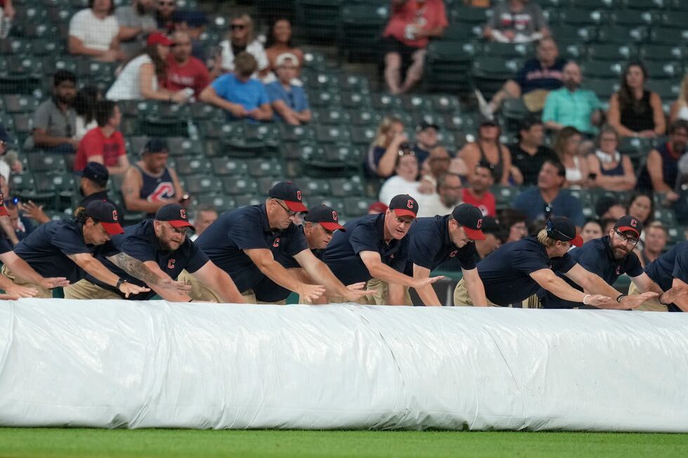 The Cleveland Guardians grounds crew rolls out the tarp for a rain delay after the fifth...