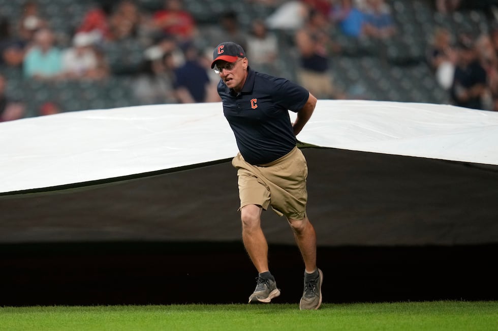 The Cleveland Guardians grounds crew brings out the tarp for a rain delay after the fifth...
