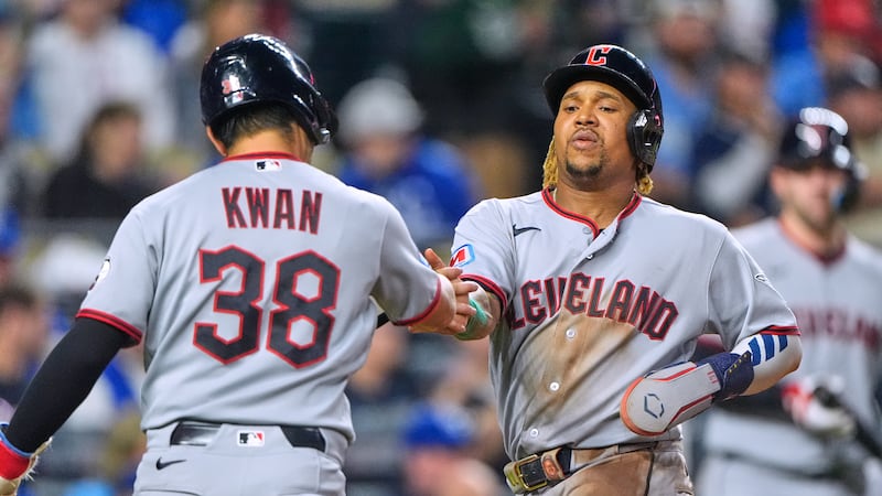 Cleveland Guardians' Steven Kwan (38) and Jose Ramirez celebrate after scoring on a single by...