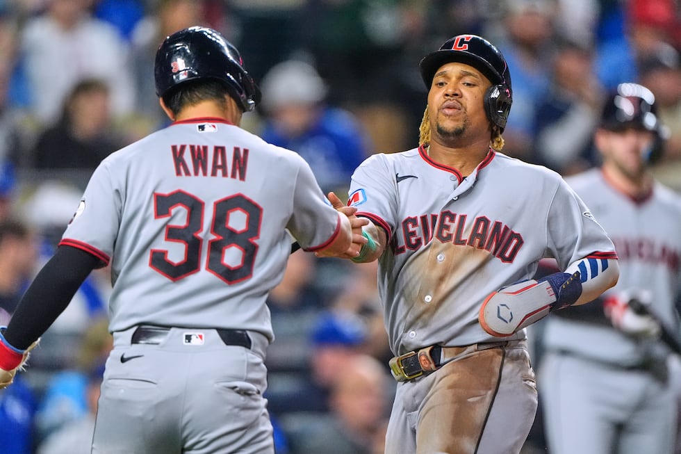 Cleveland Guardians' Steven Kwan (38) and Jose Ramirez celebrate after scoring on a single by...