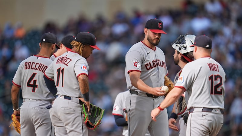 Cleveland Guardians relief pitcher Franco Aleman, middle, right, hands the game ball to...